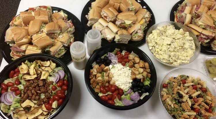 A spread of salad bowls, sandwiches and condiments